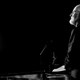 John Williams stands at a podium and looks at a darkened crowd.